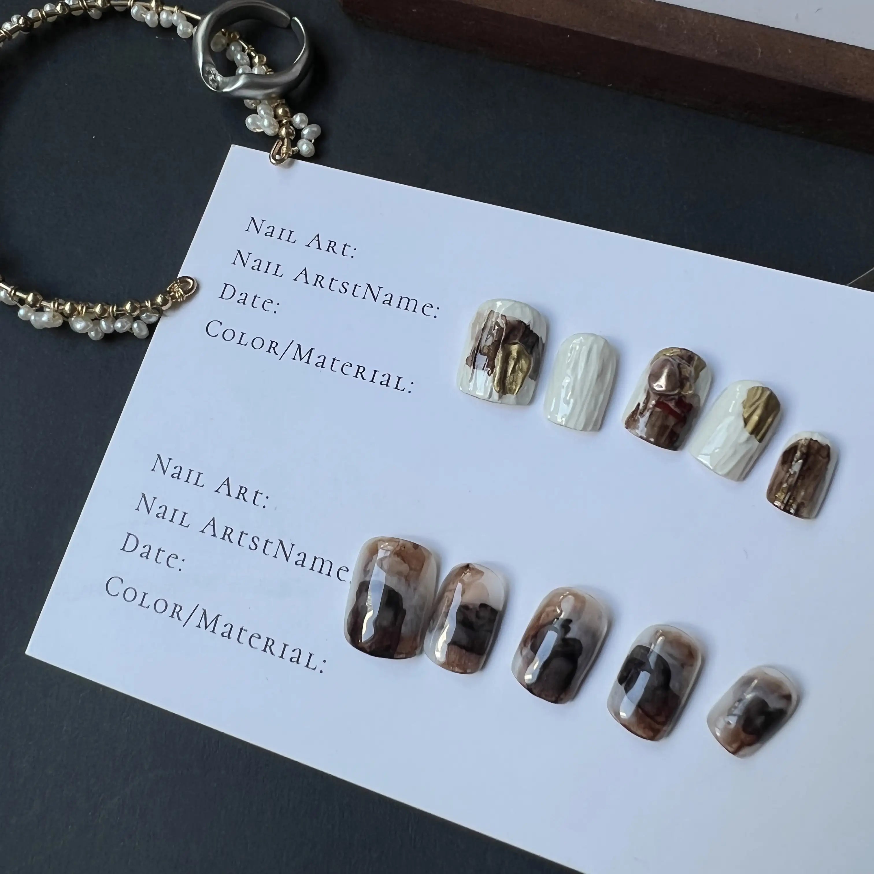 A set of press on nails in marble mocha, creamy white, and gold foil, featuring cable-knit texture and glossy finish, displayed on a card.