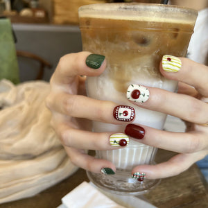 Hand holding a cup of iced coffee with decorated nails in a casual setting
