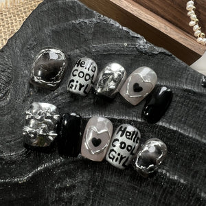 Silver and black charms with 'Hello cool Girl!' text on a dark surface