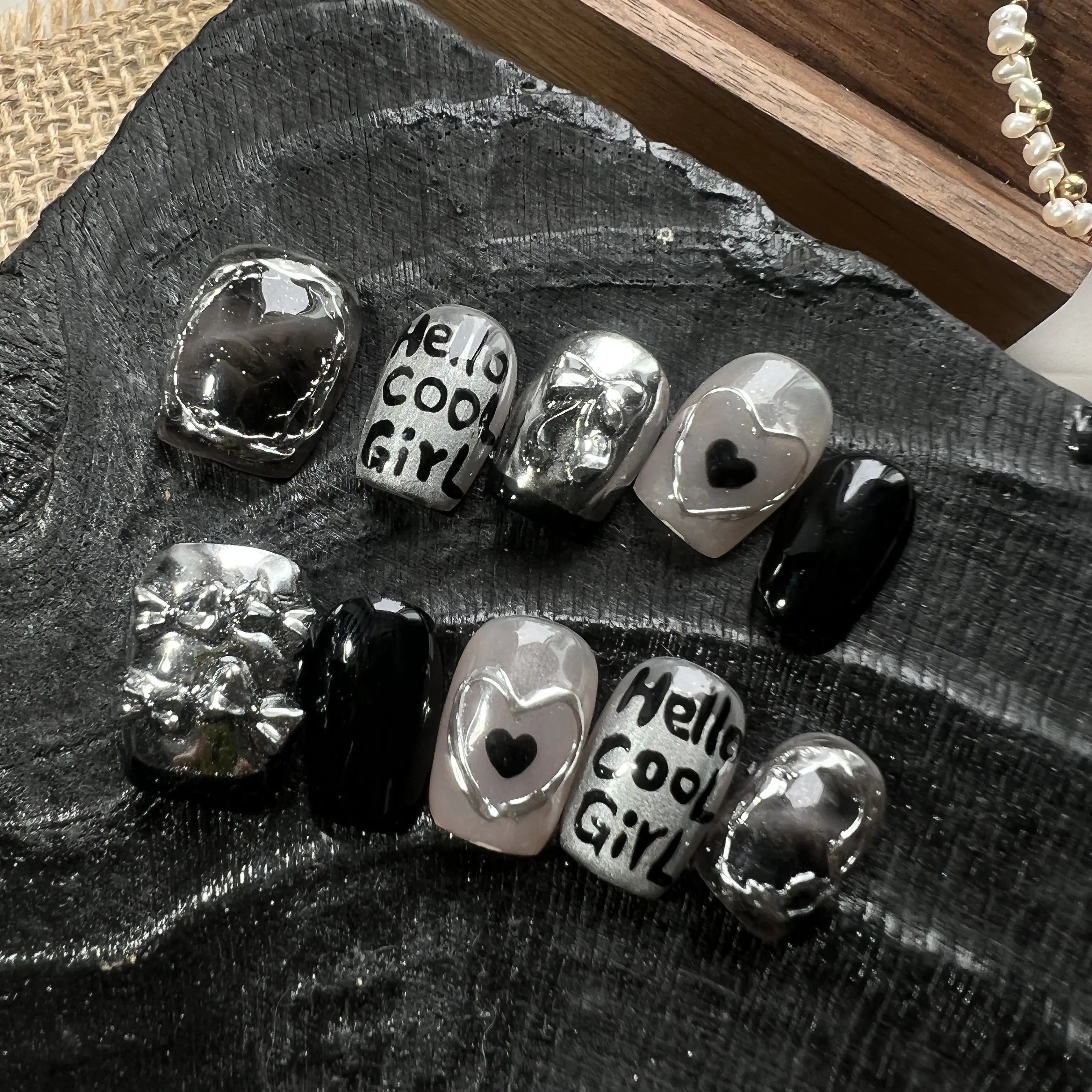 Silver and black charms with 'Hello cool Girl!' text on a dark surface