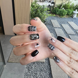 Hand with black and white nail art in an outdoor setting