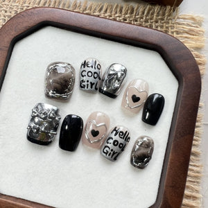 Set of nail art designs on a white surface with a wooden frame, featuring text and heart shapes.