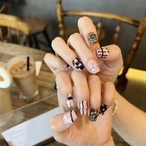 Hand with stylish nail art holding a drink in a casual setting