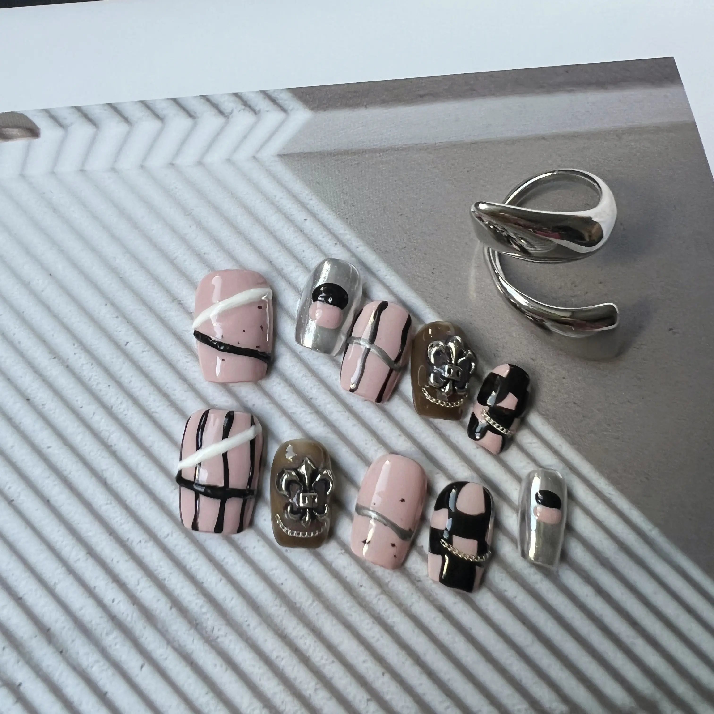 Set of nail art designs and a silver ring on a textured surface