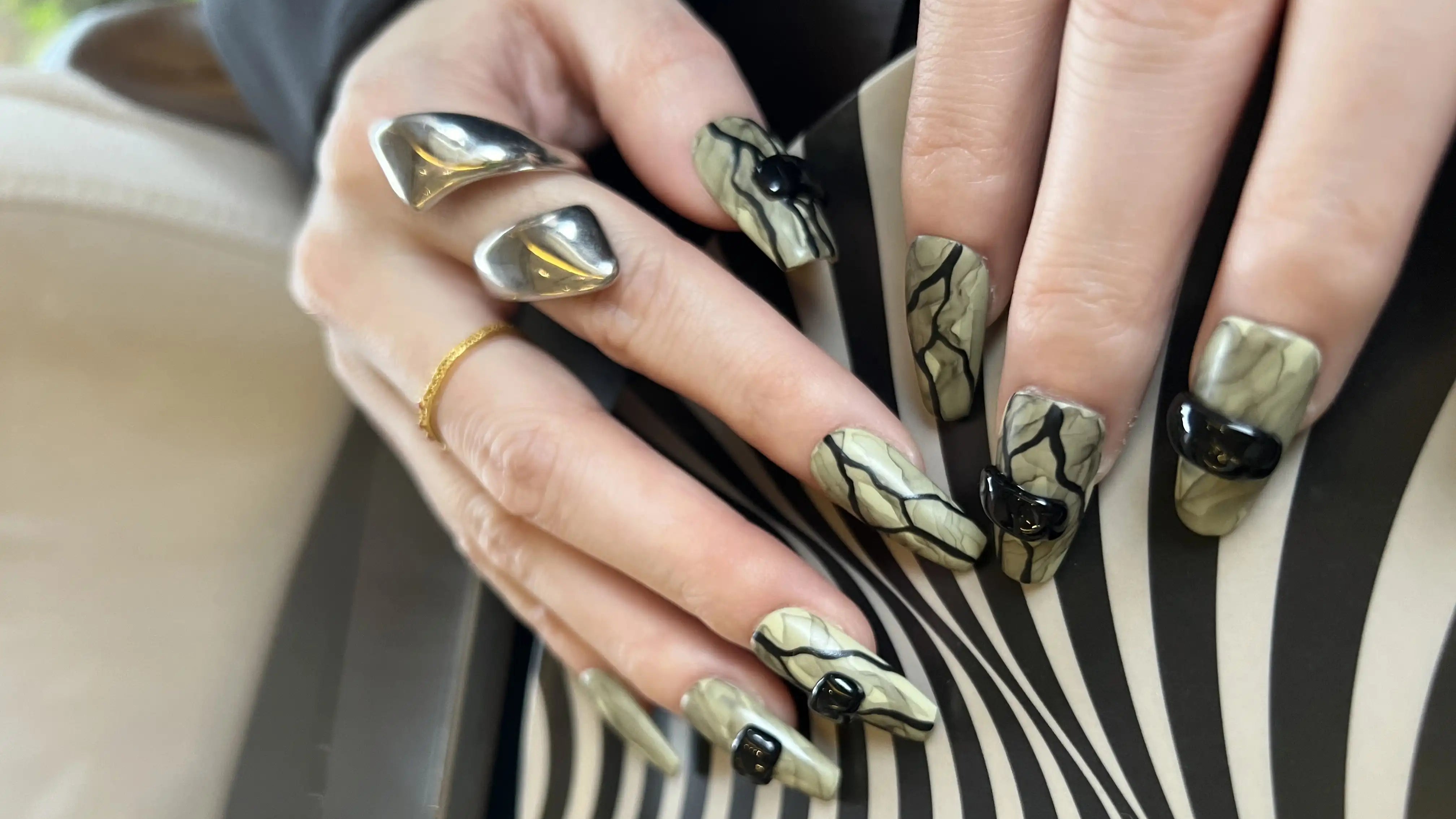 Close-up of hands with decorative nail art on a patterned background