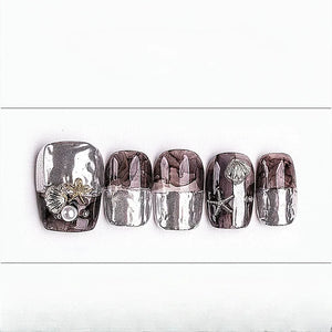 Set of five nail art designs with seashells, pearls, and starfish on a white background