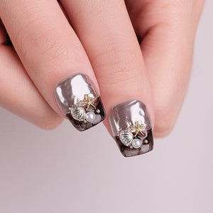Nails with silver and gold design on a light pink background