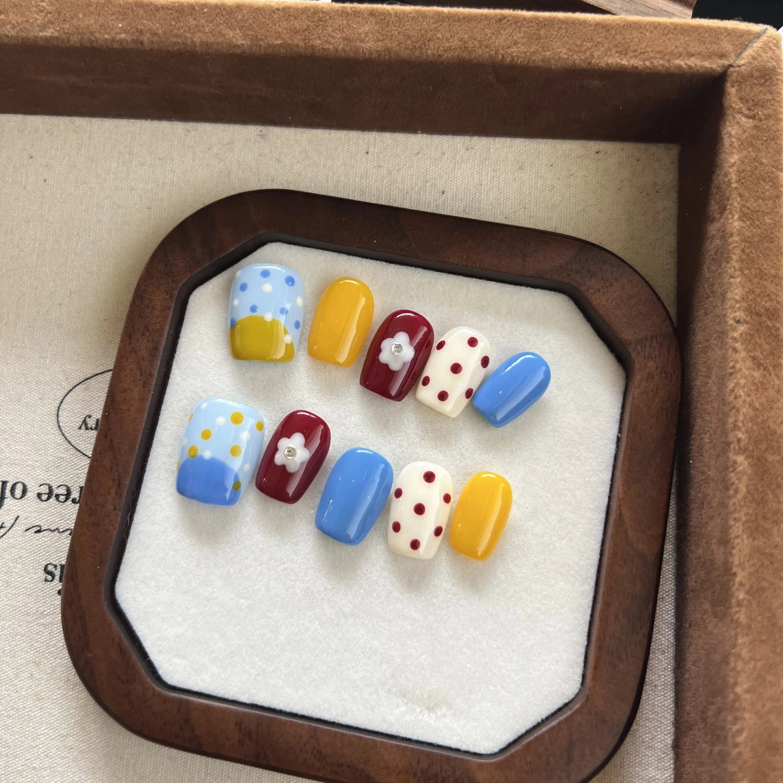 Set of colorful nail art designs in a wooden display box.