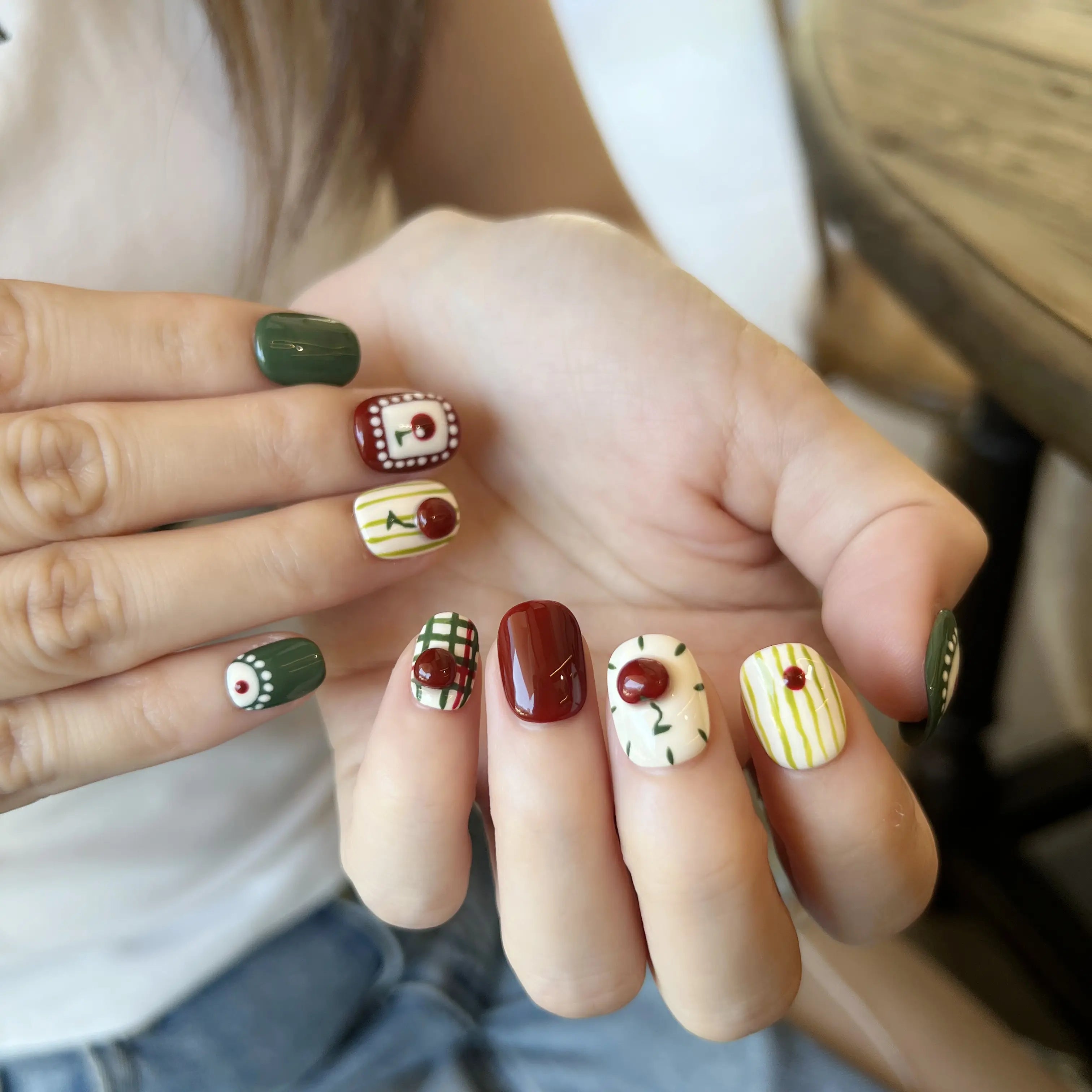Close-up of a hand with intricately designed nails featuring various patterns.