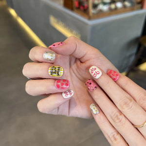 Hands with press on nails in pink, yellow, and silver glitter, featuring hand-drawn hearts, bows, and Hello Sunshine text.