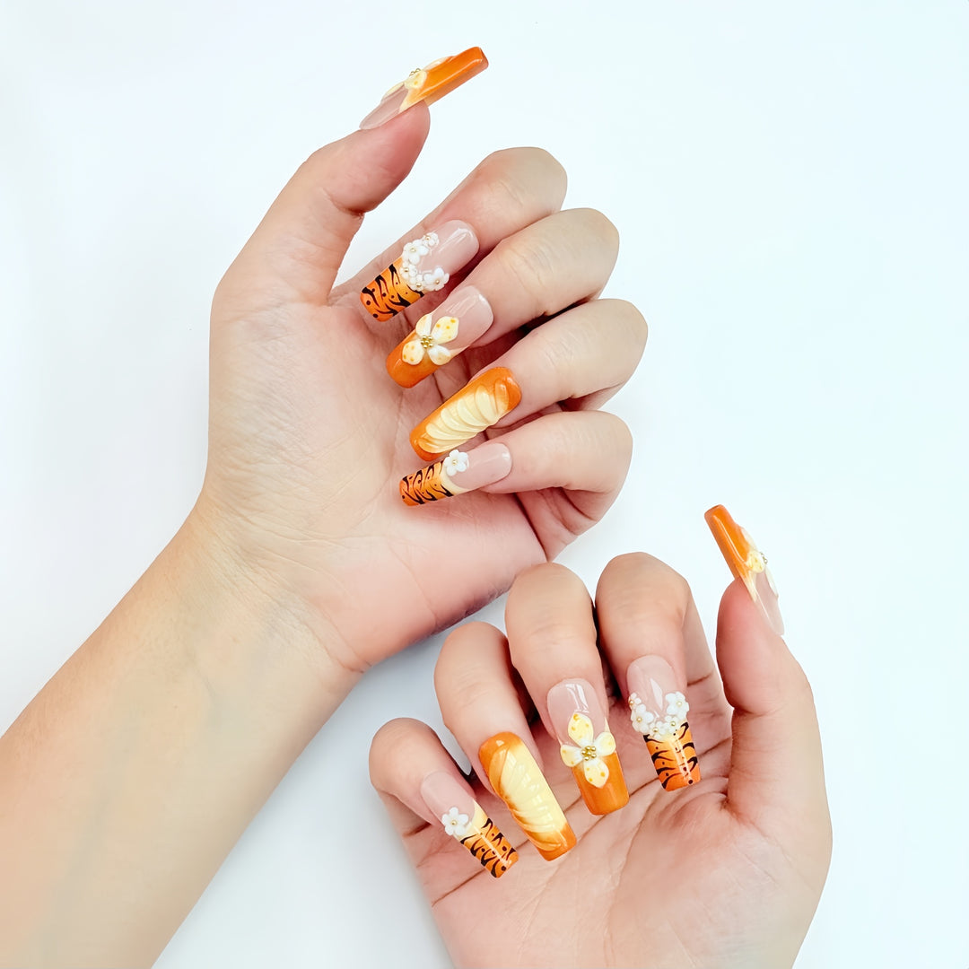 Set of orange 3D press on nails featuring handcrafted flowers and tiger stripe accents.