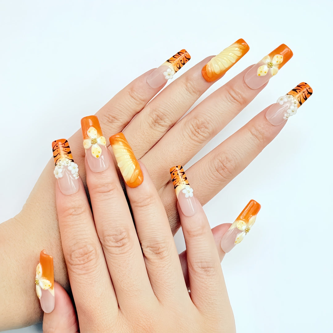 Set of orange 3D press on nails featuring handcrafted flowers and tiger stripe accents.