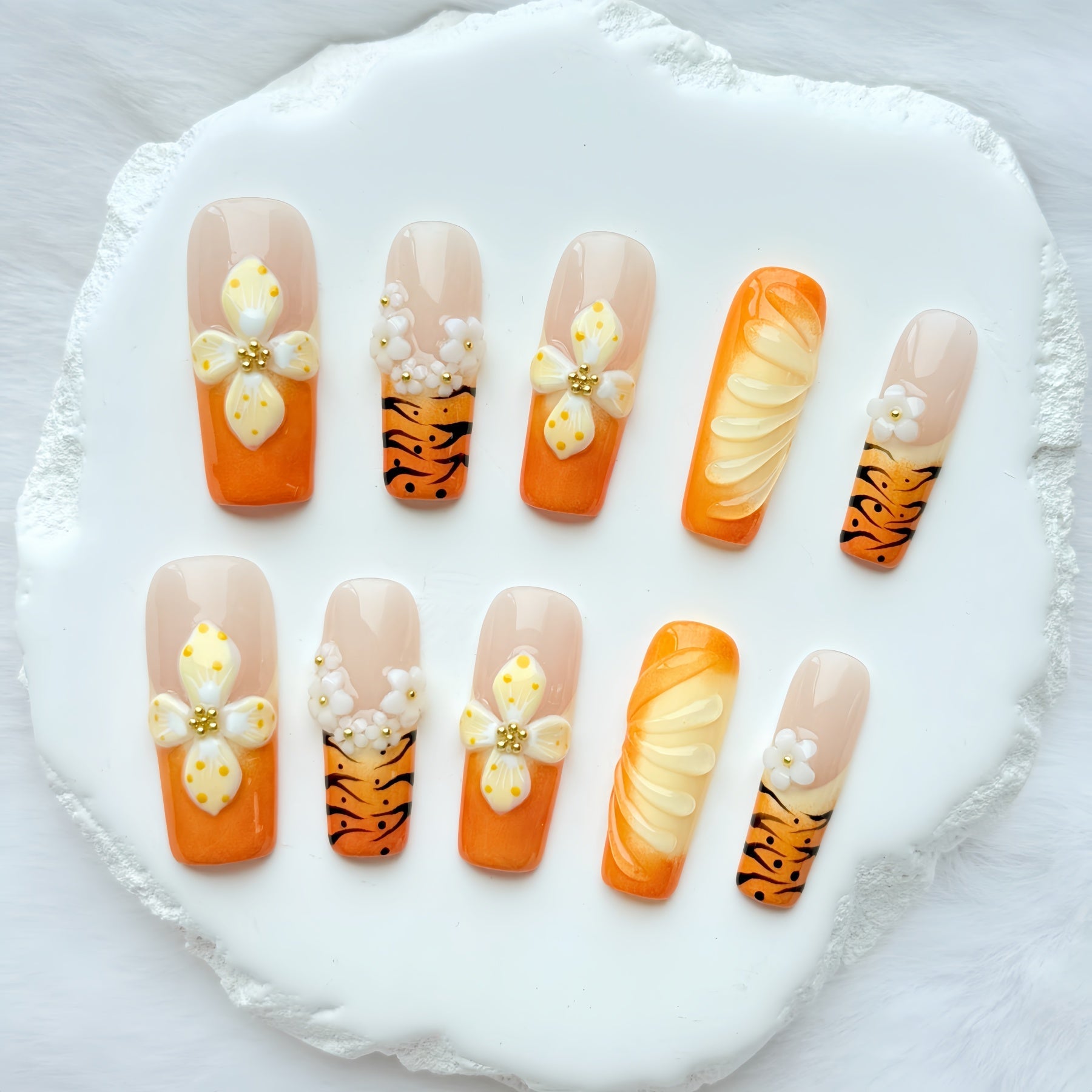 Set of orange 3D press on nails featuring handcrafted flowers and tiger stripe accents.