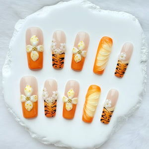 Set of orange 3D press on nails featuring handcrafted flowers and tiger stripe accents.