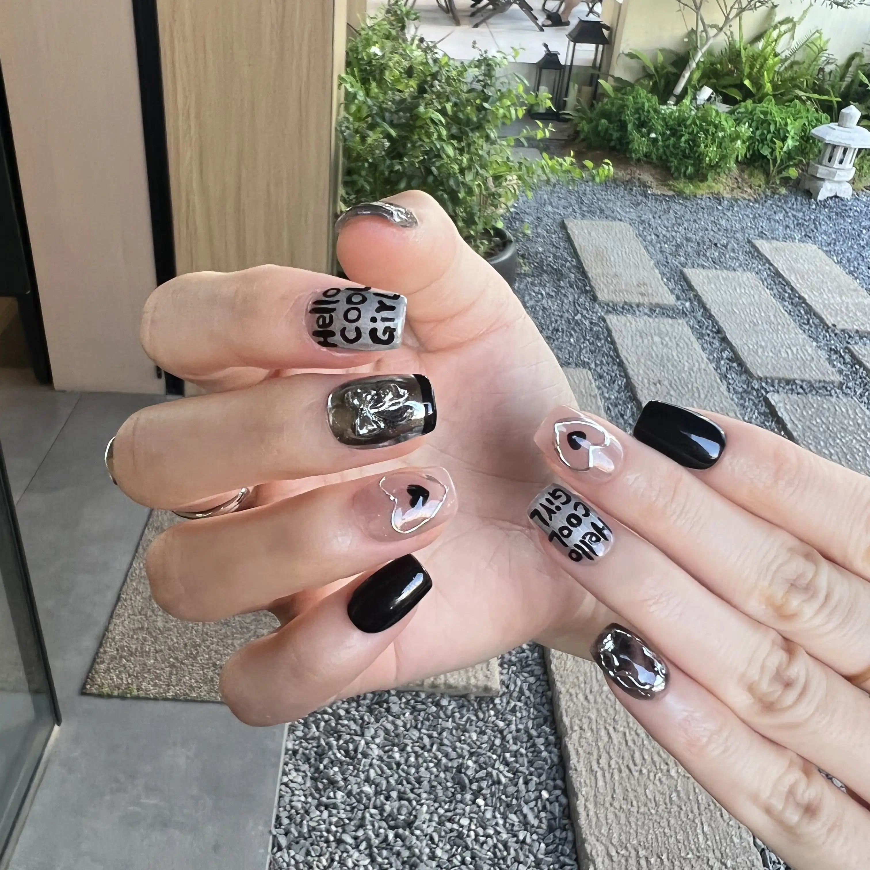 Hand with black and white nail art in an outdoor setting