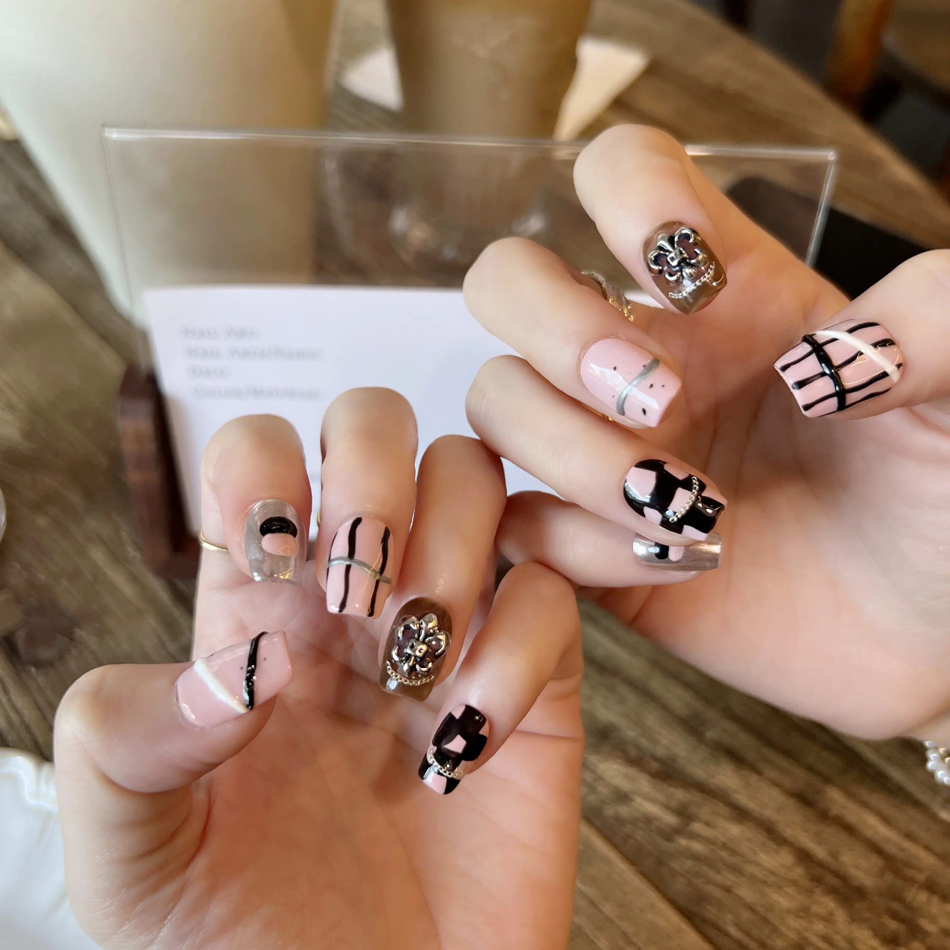 Close-up of hands with stylish nail designs on a wooden surface.